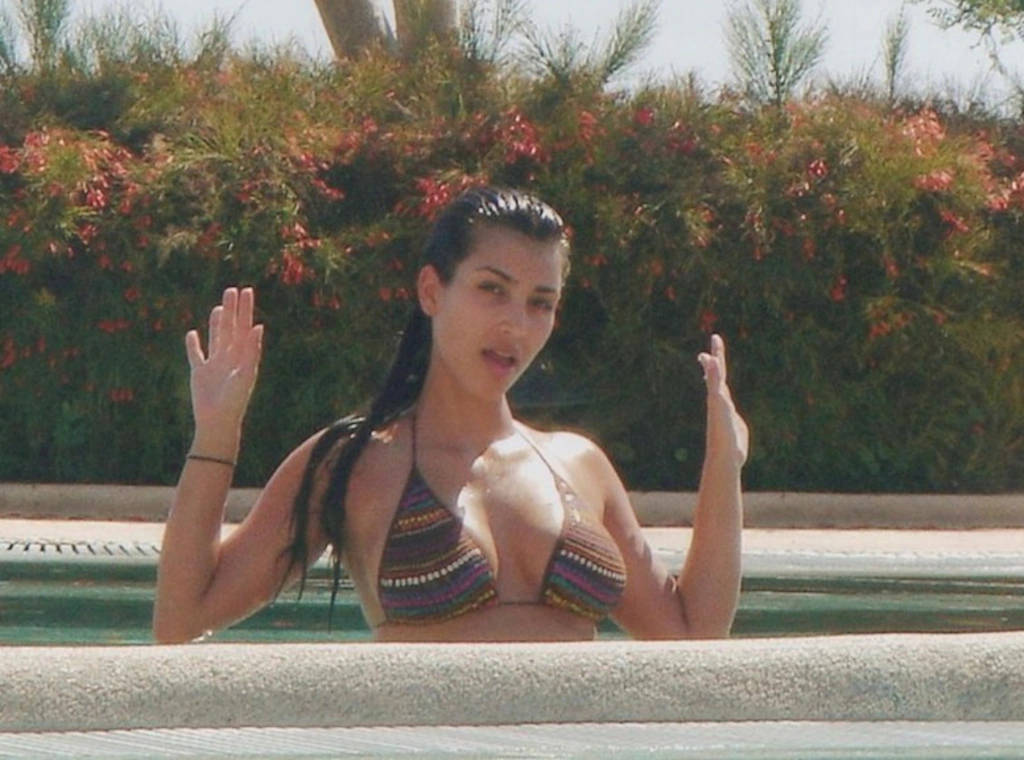 im Kardashian gazes downward while leaving the beach on August 2, stunning in a swimsuit as friend Sara Foster humorously comments on her look
